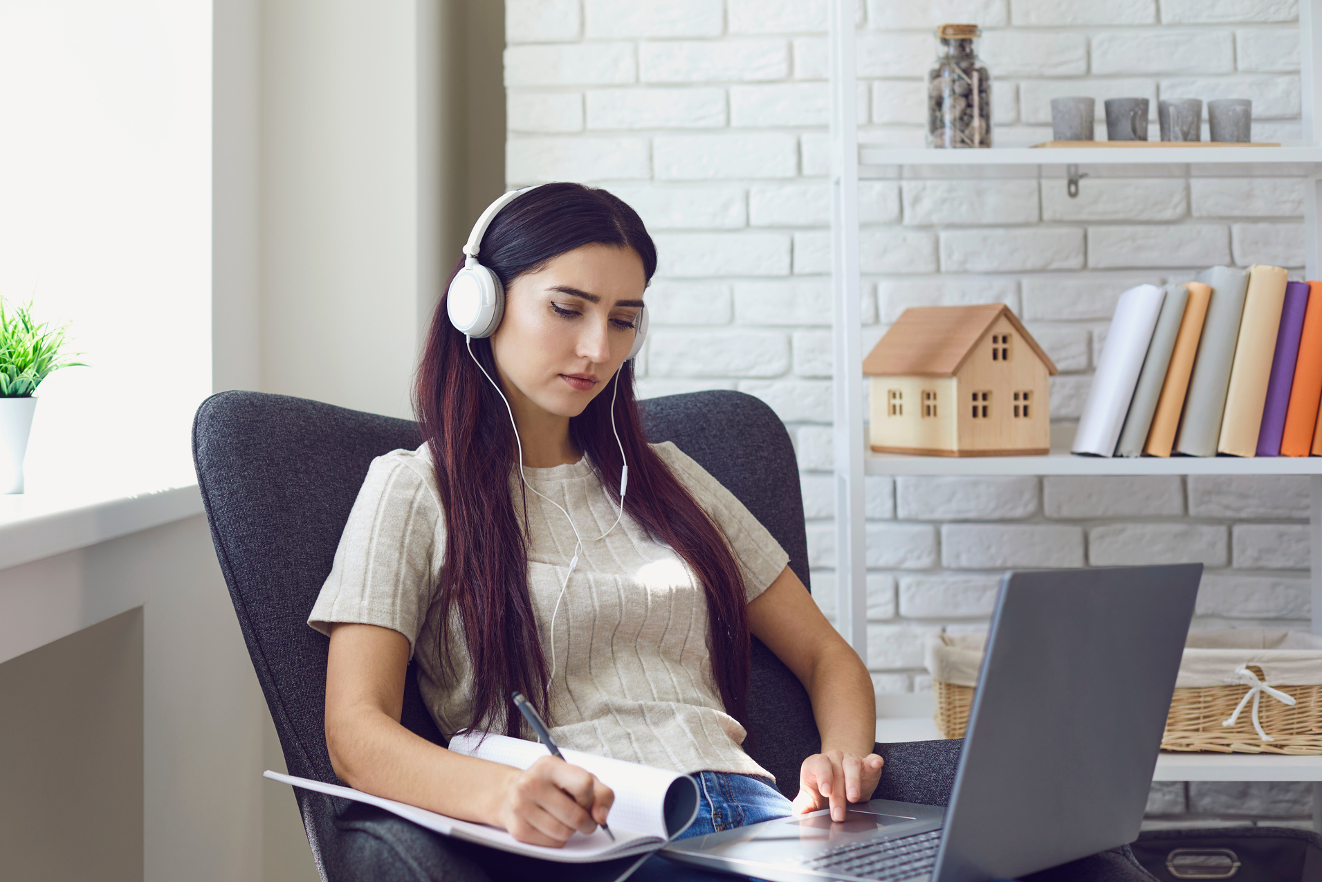 Woman in Headphones and Making Notes during Online Lesson at Home on Laptop